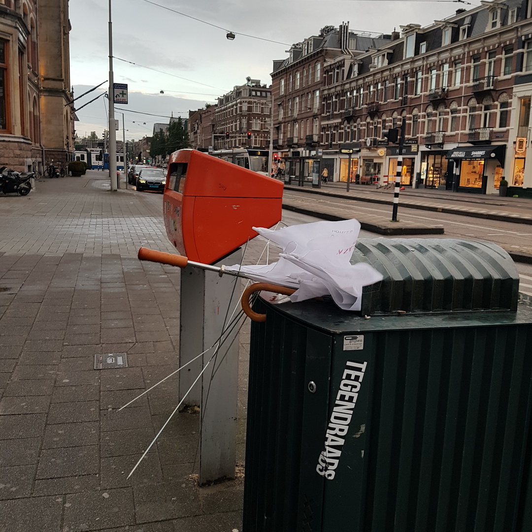 White Brolly and a brolly of unknow colour in a green Bin.