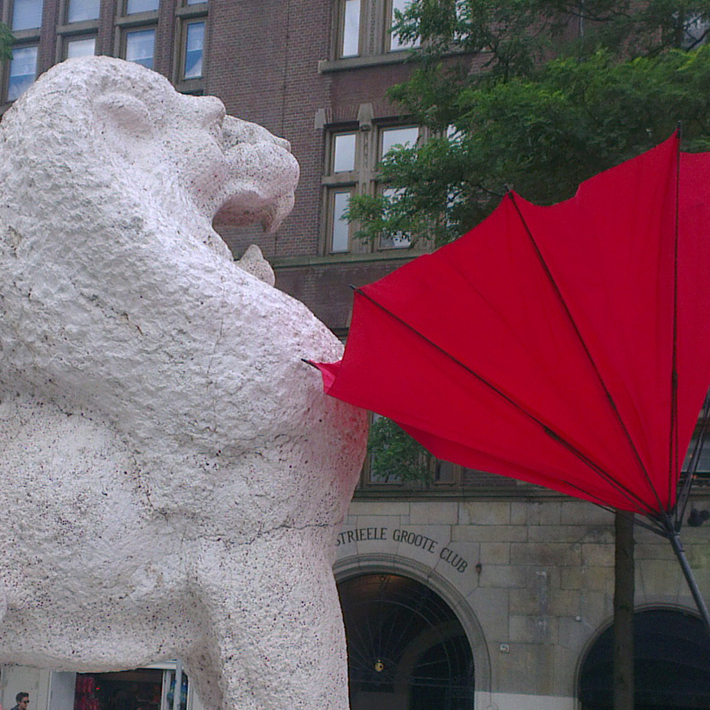 Statue of a lion "scares" of a broken red brolly stuck in a traffic sign