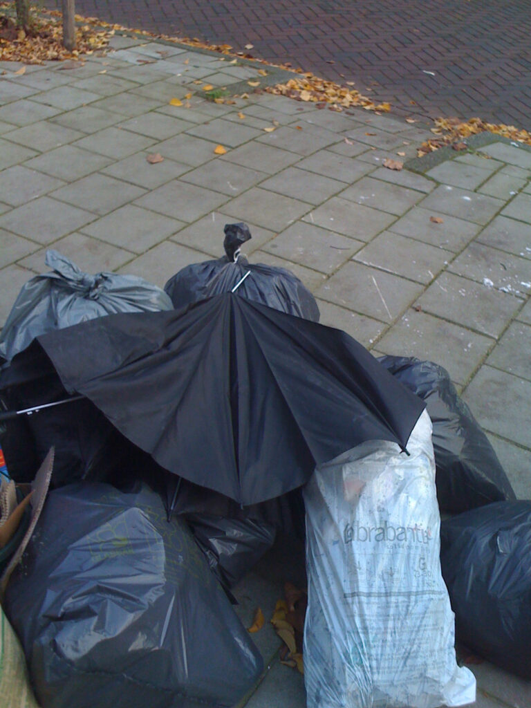 Dumbed broken brolly on a pile of garbage. All on a corner of a street.